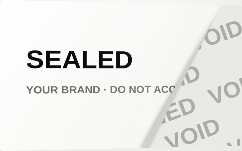 Tamper-evident adhesive label sample. Peel it and it leaves "OPENED / VOID" behind. It can't be put back unnoticed.